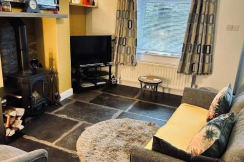 a living room with a couch and a television at Butterside Cottage in Burtersett near Hawes in Hawes