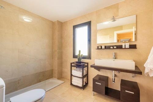 ein Badezimmer mit einem Waschbecken, einem WC und einem Spiegel in der Unterkunft Resort Marbella Pools Family Golf Wifi Children in Estepona