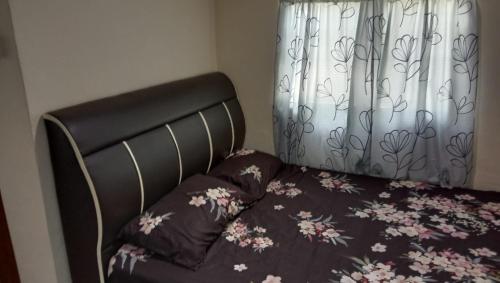 a bed with a black headboard and a curtain at Kubang Sepat HomeStay in Ayer Hitam