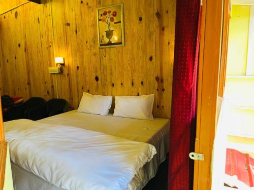 a bed in a room with a wooden wall at Peace space resort in Nainital