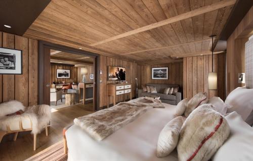 a bedroom with a large bed and a living room at Hôtel Barrière Les Neiges Courchevel in Courchevel