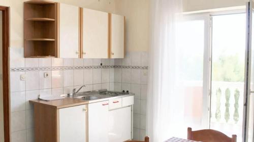 una cucina con armadi bianchi, lavandino e finestra di One bedroom apartement with sea view enclosed garden and wifi at Razanac a Ražanac (Rasanze)