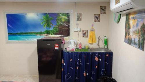 a kitchen with a refrigerator and a picture of a beach at Kubang Sepat HomeStay in Ayer Hitam