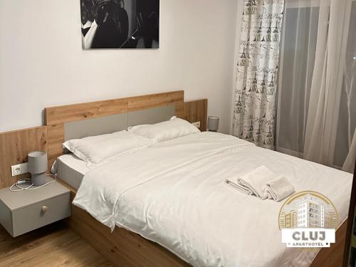 1 dormitorio con 1 cama grande con sábanas blancas en Cluj Viva Aparthotel en Cluj-Napoca