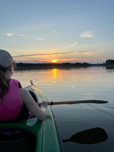 a young girl paddling a canoe on a lake at Beztroska Zatoka - agroturystyka Jacuzzi & Sauna in Połajewo