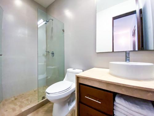 een badkamer met een toilet, een wastafel en een douche bij Tropical Retreat. Sassy 2BR Home in Bahia Principe in Akumal