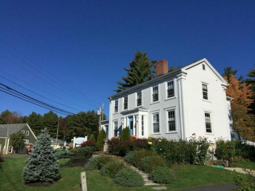 a white house with a christmas tree in the yard at 2 River Road Inn Cottages in Cape Neddick