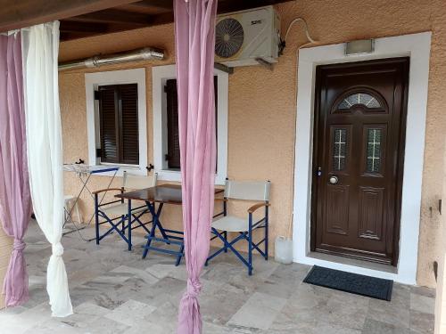 a porch with a table and chairs and a door at Marilena's Beach House in Agios Georgios Pagon