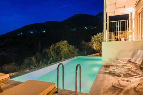 a swimming pool at night with mountains in the background at Punentes Villa in Divarata