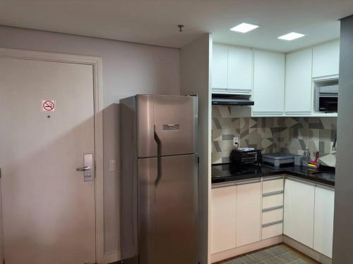 a kitchen with a stainless steel refrigerator and white cabinets at Flat- mercure c/ quarto, sala e coz - Moema in São Paulo