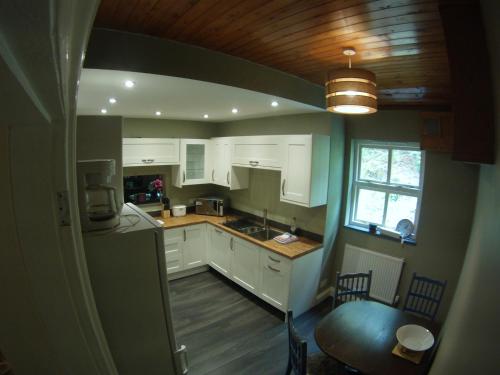 a kitchen with white cabinets and a table and a window at Padarn Apartment at Glanybala Holidays in Llanberis