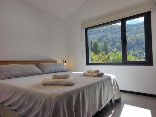 1 dormitorio con 1 cama con 2 toallas en Depto moderno con estacionamiento/ AlquilaMiCasa en San Martín de los Andes