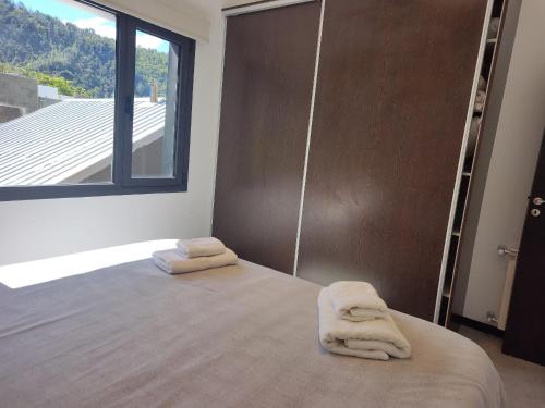 1 dormitorio con 1 cama con toallas en Depto moderno con estacionamiento/ AlquilaMiCasa en San Martín de los Andes