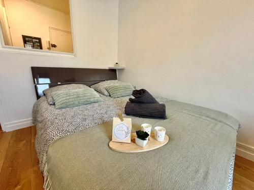 - un lit avec un plateau avec deux tasses et un livre dans l'établissement L'escapade Cosy-Hyper centre-Proxy Plage, à Dieppe