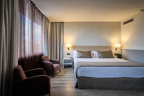 a hotel room with a bed and a chair at Catalonia Gran Hotel Verdi in Sabadell