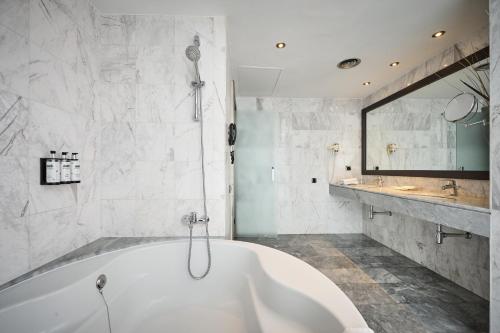 a white bathroom with a tub and a sink at Catalonia Gran Hotel Verdi in Sabadell
