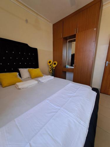 1 dormitorio con 1 cama blanca grande con almohadas amarillas en Petra Homes, en Mombasa