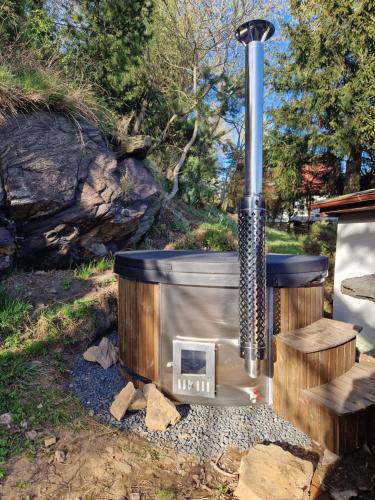 a wood fired stove in a yard with a bench at Jelení dřevěnice s vlastní vířivkou in Horní Halže