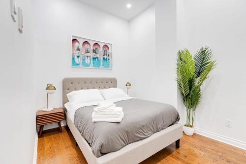 - une chambre blanche avec un lit et une plante en pot dans l'établissement M11 Stylish & Modern 3BR downtown MTL, à Montréal