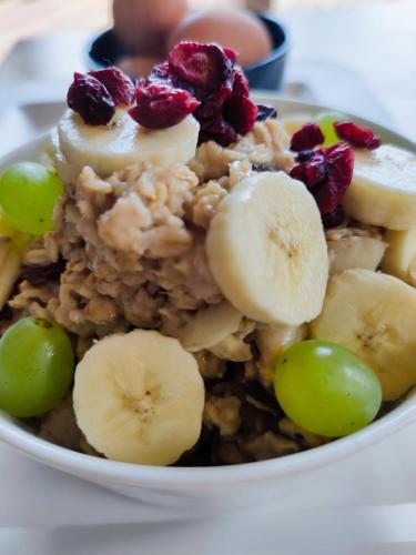 a bowl of food with bananas grapes and nuts at Slow Huts in Miedzygorze