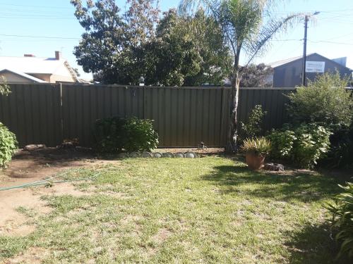 een achtertuin met een hek en een tuin met gras bij Peaceful Haven in Adelaide