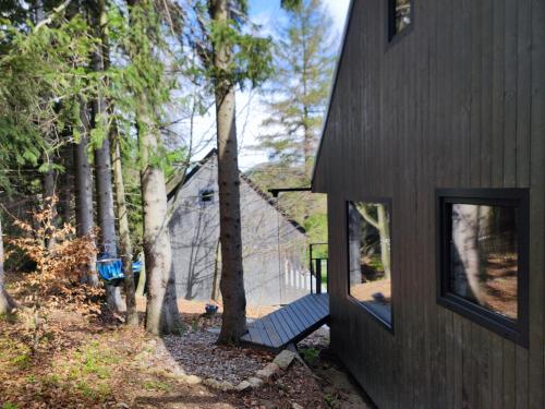 a black house with a bench in front of it at Slow Huts in Miedzygorze