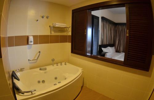 ein Badezimmer mit einer Badewanne und einem großen Spiegel in der Unterkunft MySuite Studio Apartment Melaka Waterpark Resort in Ayer Keroh