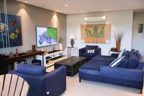a living room with blue couches and a tv at Condomínio Quinta de Juquehy - Prime Experience in Juquei