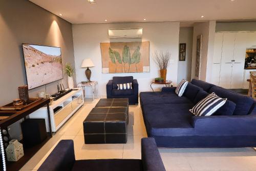 a living room with blue couches and a flat screen tv at Condomínio Quinta de Juquehy - Prime Lok in Juquei