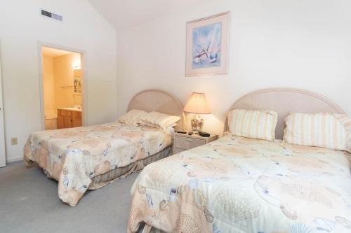 een slaapkamer met 2 bedden, een lamp en een spiegel bij Tidewater- Teal lake #2521 in North Myrtle Beach