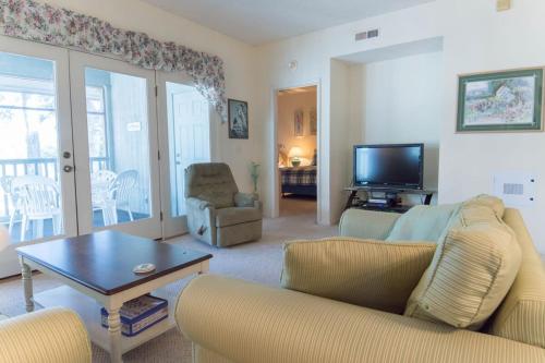 a living room with a couch and a table and a tv at Tidewater Teal Lake 1323 in North Myrtle Beach