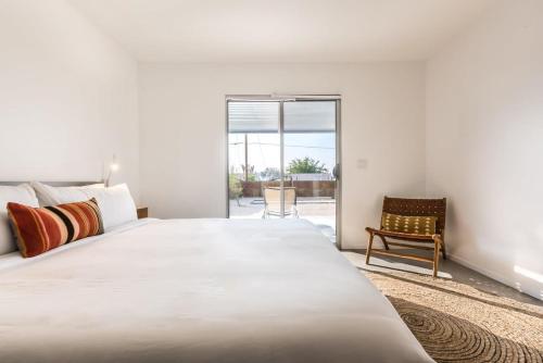 a bedroom with a large white bed and a chair at Hidden Valley Cottage - Modern Home in JT Hot Tub in Joshua Tree