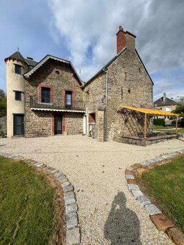 une grande maison en pierre avec une aire de jeux en face de celle-ci dans l'établissement Gîte de la petite tour, à Pontorson