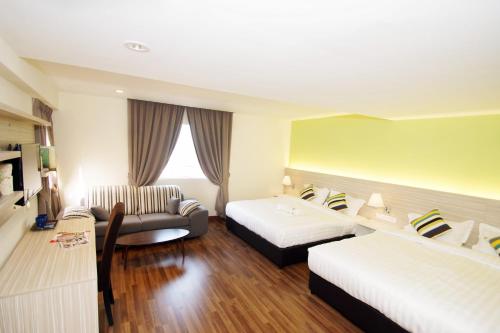 a hotel room with two beds and a couch at Good Luck Inn in Ayer Itam