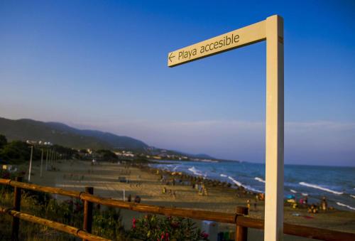 a sign on a beach with people on the beach at Apartments Kione Playa Romana Park in Alcossebre