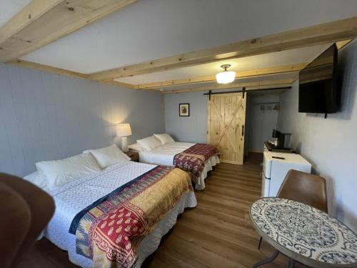 a room with two beds and a table and a television at Sweet Forest Breeze, A Cook Forest Inn in Marienville