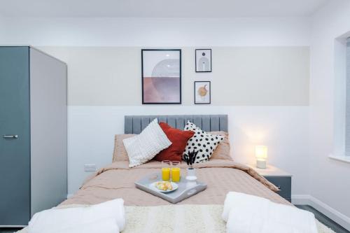 a bed with a tray with two glasses of orange juice at Brand New Modern 2 Bed in Didsbury in Manchester