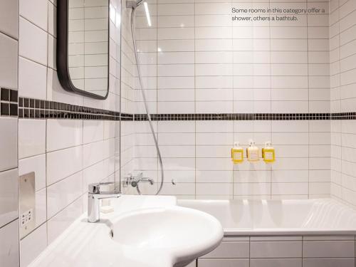La salle de bains blanche est pourvue d'un lavabo et d'une baignoire. dans l'établissement Bedford Corner Hotel, à Londres