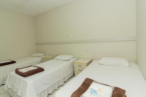 2 łóżka w pokoju z białymi ścianami w obiekcie Hotel Ourinhos - Centro de São Paulo - Próximo 25 de Março e Brás - By Up Hotel w São Paulo