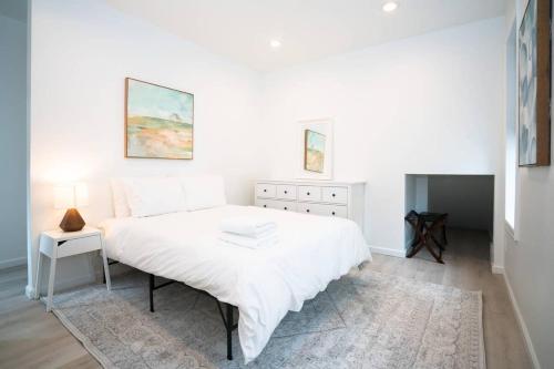 a white bedroom with a large white bed and a rug at The Mile High Escape in Curtis Park in Denver