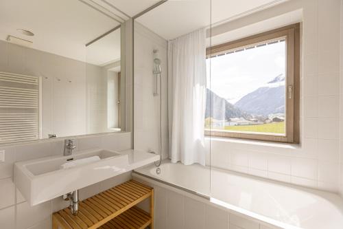 a white bathroom with a sink and a window at Alpenrock Schladming by ALPS RESORTS in Schladming