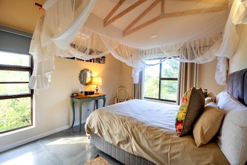 a bedroom with a bed with curtains and windows at Ndlovu Bushvilla at Elephant Rock Eco Estate in Mica