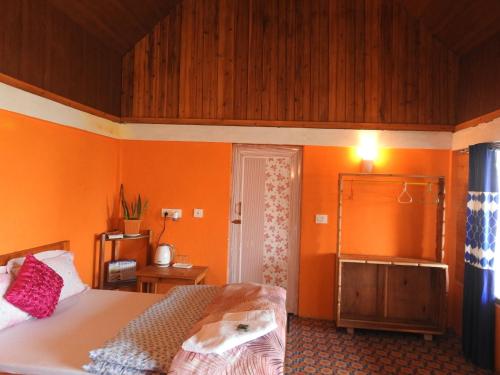 1 dormitorio con paredes de color naranja y 1 cama. en Tribal Homestay Sittong, en Mangpu
