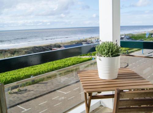a potted plant sitting on a table on a balcony overlooking the beach at Villa aan Zee in Noordwijk