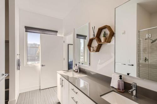 a white bathroom with two sinks and a mirror at Modern 2BR Condo Walk to all RiNo Attractions in Denver