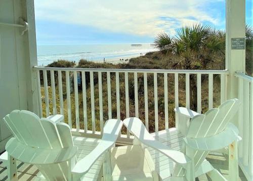 two white chairs on a porch with a view of the beach at The Sea Shed- Ocean Front Condo in Myrtle Beach