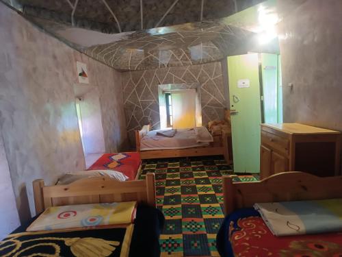 Habitación con 3 camas y espejo. en Lodge Le Noyer en Aït Imi