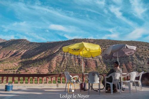 a man sitting at a table under two umbrellas at Lodge Le Noyer in Aït Imi