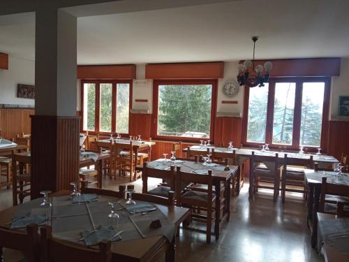 jadalnia ze stołami, krzesłami i oknami w obiekcie Stella Alpina Fabrezza w mieście Saviore dellʼAdamello