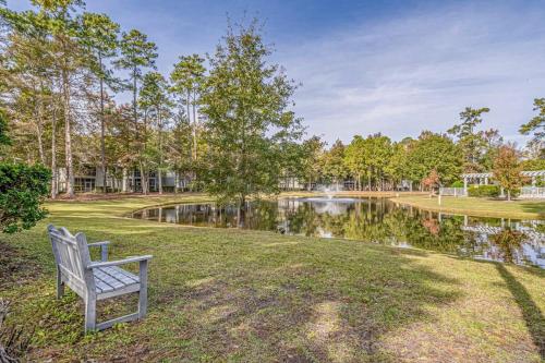 a park bench sitting in the grass next to a pond at Teal Lake 1413 in North Myrtle Beach